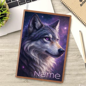 Puede incluir: Un cuaderno con una ilustración de lobo. La portada presenta un retrato detallado de un lobo con ojos morados sobre un fondo estrellado púrpura y azul. La palabra "Name" está impresa en la parte inferior.