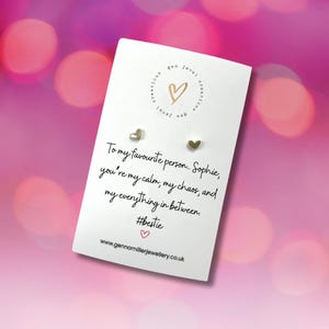 Pode incluir: Um cart&atilde;o branco com brincos de cora&ccedil;&atilde;o dourados. O cart&atilde;o tem o texto: "Para a minha pessoa favorita, Sophie, voc&ecirc; &eacute; a minha calma, o meu caos e tudo mais. #bestie". O cart&atilde;o tamb&eacute;m tem um logotipo de cora&ccedil;&atilde;o.