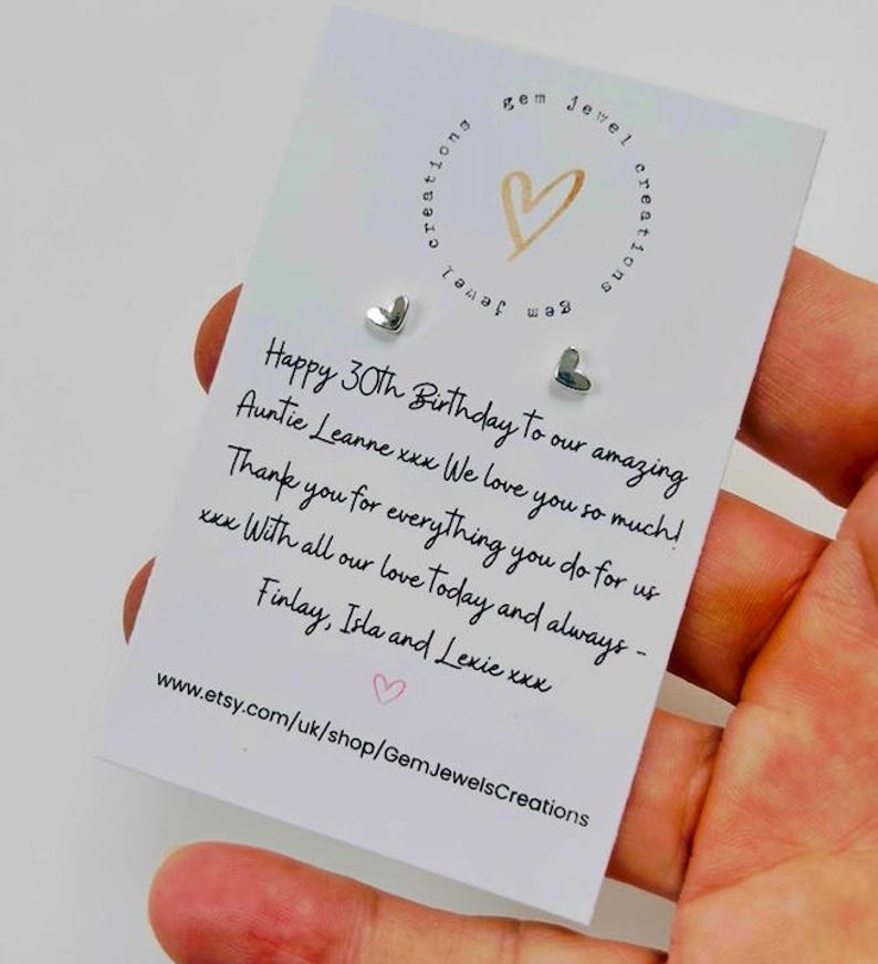 Pode incluir: Brincos pequenos em forma de cora&ccedil;&atilde;o prateado em um cart&atilde;o branco. O cart&atilde;o tem texto manuscrito desejando um feliz 30&ordm; anivers&aacute;rio. O cart&atilde;o tamb&eacute;m tem um logotipo de cora&ccedil;&atilde;o dourado e o URL da loja Etsy.