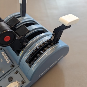May include: Close-up of a blue Airbus flight simulator control panel with black and white switches and knobs. The panel features a throttle lever with a white handle and a red button on the throttle.