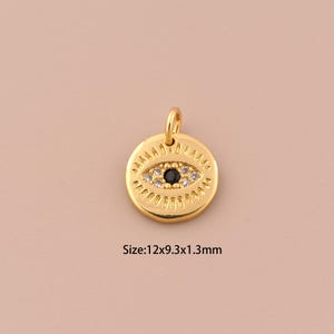 Puede incluir: Encanto dorado con un diseño de ojo turco negro y blanco. El encanto mide 12 mm de ancho, 9,3 mm de alto y 1,3 mm de grosor.