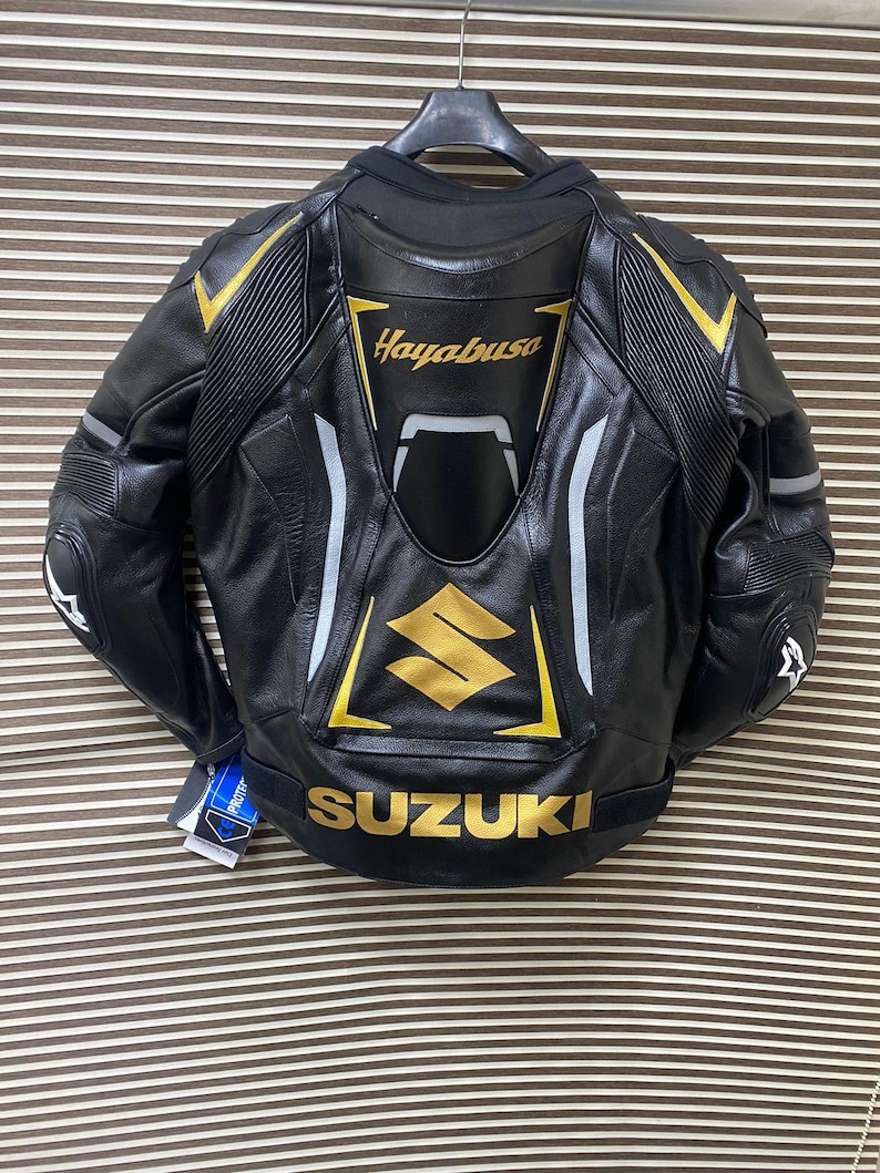 May include: Black leather motorcycle jacket with gold and white accents. The jacket features the words "Hayabusa" and "SUZUKI" on the back.