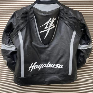 May include: Black leather motorcycle jacket with white accents and the word "Hayabusa" printed on the back. The jacket has a large white kanji character on the back.