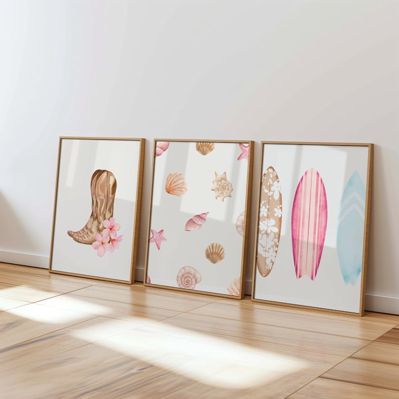 May include: Three framed watercolor prints. The left print features a brown cowboy boot with pink flowers. The middle print features a white background with pink and brown seashells and a starfish. The right print features three surfboards with pink, white, and blue stripes.
