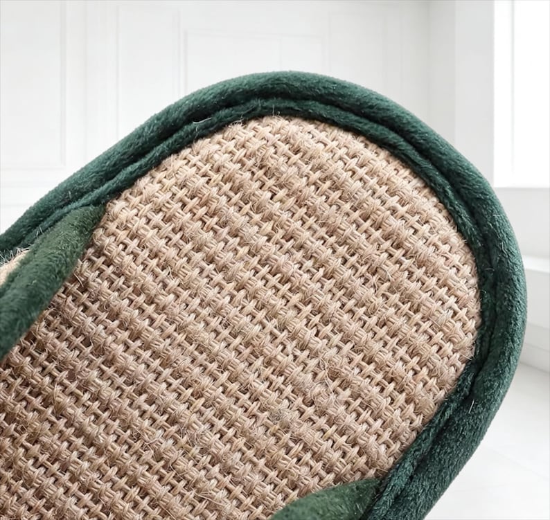 Pu&ograve; includere: Primo piano di una pantofola beige intrecciata con un bordo verde scuro. La superficie della pantofola presenta un motivo strutturato a tratteggio incrociato. Il bordo verde scuro borda il bordo della pantofola, fornendo un accento di contrasto.