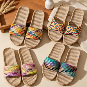 Puede incluir: Cuatro pares de sandalias tipo chancla con plantillas de paja tejida en color beige y tiras trenzadas de colores. Las tiras muestran varios patrones de hilos rojos, amarillos, verdes, azules y morados. Las sandalias están agrupadas.