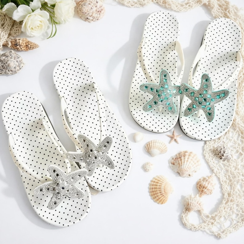 May include: White polka dot flip-flops with starfish embellishments. The flip-flops have a white strap and are decorated with a silver and turquoise starfish design. The image also includes seashells and flowers, suggesting a beach theme.