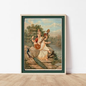 Op de afbeelding: Ingelijste vintage print van een zittende figuur die een snaarinstrument bespeelt. De figuur draagt witte en rode kleding en heeft meerdere armen. Er is ook een pauw aanwezig. De achtergrond toont een rivier en bomen.
