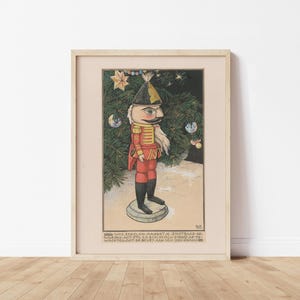 May include: Framed vintage print of a nutcracker soldier in a red uniform, black boots, and a tall hat. The artwork features a Christmas tree with baubles and text at the bottom. The print is in a light-coloured wooden frame.