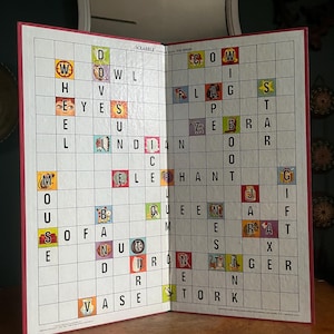 May include: Open Scrabble game board with red trim, displaying various words spelled out on the grid. Words include "OWL", "EYES", "INDIAN", "SOFA", "ZEBRA", and "TIGER". The game is open on a wooden surface.