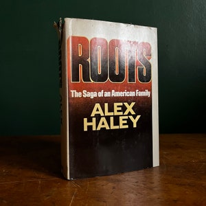 May include: A paperback copy of the book "Roots: The Saga of an American Family" by Alex Haley. The cover is white with a black and orange title and author's name.