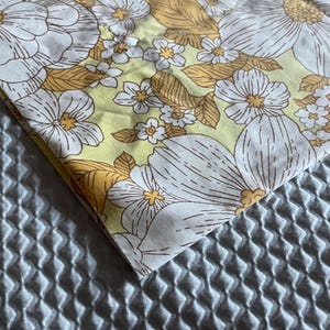 Pode incluir: Um close-up de um tecido amarelo com um padr&atilde;o floral branco. O tecido tem um toque vintage e &eacute; perfeito para projetos de artesanato.