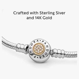 May include: A silver and gold Pandora bracelet with a round charm that has a gold center with clear stones and the word "Pandora" written around the edge.