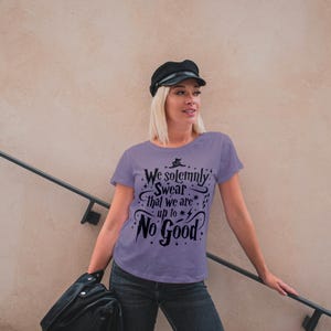 Op de afbeelding: Een paars T-shirt met een zwarte afbeelding met de tekst "We solemnly swear that we are up to no good".