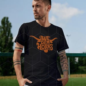 May include: A black t-shirt with an orange graphic of a longhorn bull with the text "We Dem Horns" on it.
