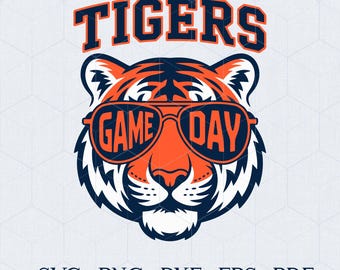 May include: A graphic of a tiger's face wearing sunglasses with the words "GAME DAY" on the lenses. The word "TIGERS" is above the tiger's head. The design is in orange, navy blue, and white.