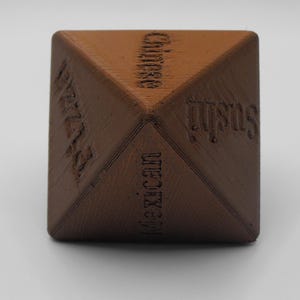 May include: A brown, pyramid-shaped object with the words "Mexican", "Sushi", "Chinese", and "Pizza" etched into its sides. The object is sitting on a white surface.