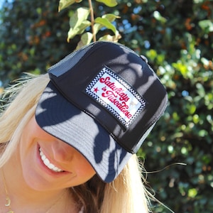 May include: A black mesh trucker hat with a white patch that says "Saturdays in Tuscaloosa" in red lettering. The hat has a white star and a red bull on the patch.