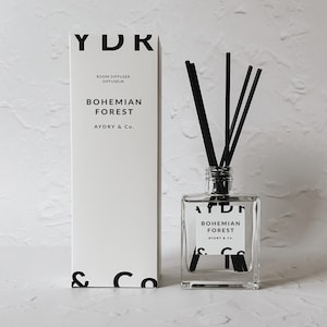 May include: A white box with black text that reads "YDR Room Diffuser Diffuseur Bohemian Forest AYDRY & Co." and a clear glass bottle with black text that reads "YDR Bohemian Forest AYDRY & Co." and black reeds.