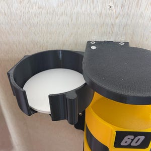 Puede incluir: Un soporte de pared negro y amarillo que presenta una secci&oacute;n circular con base blanca y una columna vertical con tres compartimentos amarillos apilados. Cada compartimento muestra una etiqueta negra con los n&uacute;meros 60, 120 y 240.
