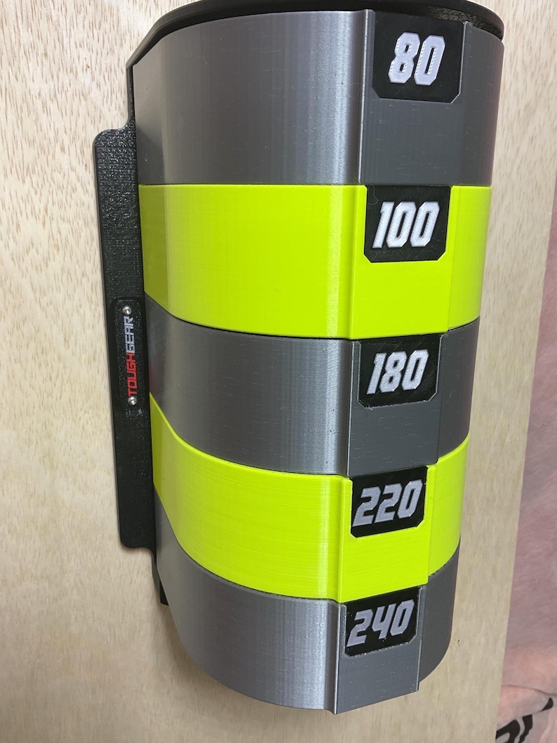 Puede incluir: Un organizador de almacenamiento montado en la pared con bandas horizontales alternas en gris y amarillo ne&oacute;n. La unidad incluye etiquetas rectangulares negras con los n&uacute;meros blancos 80, 100, 180, 220 y 240. Un panel lateral negro muestra TOUGHGEAR en rojo.