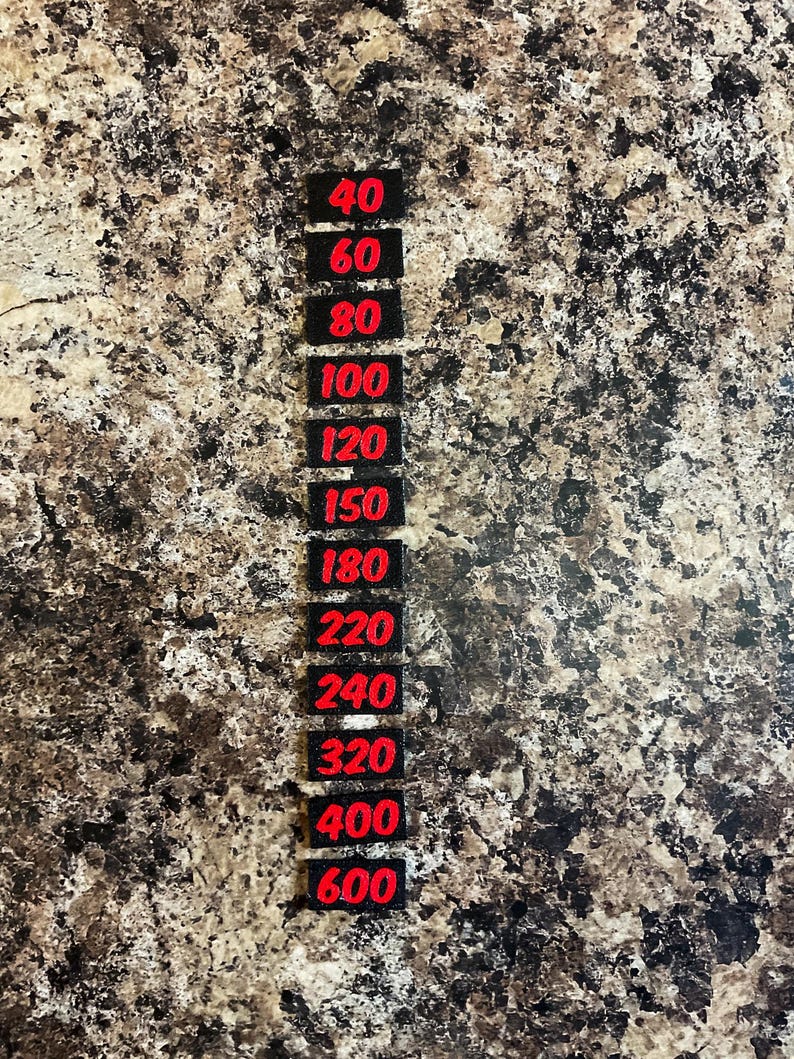 May include: A vertical column of twelve small, rectangular black labels, each featuring a bold red number. The numbers listed in descending order are 40, 60, 80, 100, 120, 150, 180, 220, 240, 320, 400, and 600, representing grit levels for sanding.