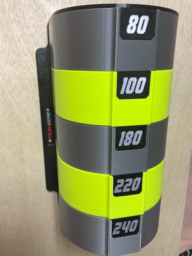 Puede incluir: Un estante de almacenamiento montado en la pared con secciones cil&iacute;ndricas alternas en gris y amarillo ne&oacute;n. Cada secci&oacute;n muestra una etiqueta rectangular negra con n&uacute;meros blancos: 80, 100, 180, 220 y 240. Una placa de montaje negra tiene la marca TOUGHGEAR.