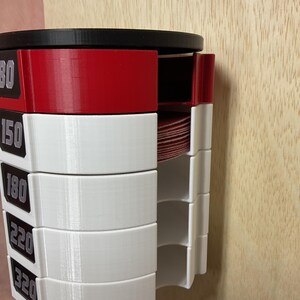 Puede incluir: Un organizador de discos de lija montado en la pared con una parte superior negra y compartimentos de pl&aacute;stico apilados en rojo y blanco. Cada secci&oacute;n est&aacute; etiquetada con los granos 80, 150, 180, 220 y 320 en texto blanco sobre fondo negro.