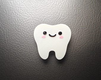 May include: A white, cartoon-style tooth with a smiling face, black eyes, and pink cheeks. The tooth is set against a dark gray textured background, creating a playful and friendly aesthetic. This item is likely a dental-themed decoration.