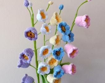 May include: A bouquet of crocheted flowers in shades of blue, pink, yellow, and purple. The flowers are shaped like bells and are arranged in a vase.