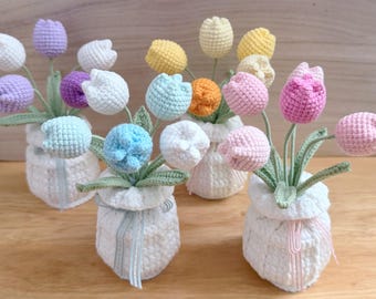 May include: Four small white crocheted pots each containing a bouquet of multi-colored crocheted tulip flowers. The tulips are in shades of white, light blue, lavender, purple, yellow, orange, and pink, with green stems and leaves.