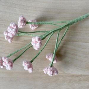 May include: A bouquet of pink crocheted flowers with green stems. The flowers have a pearl-like center.