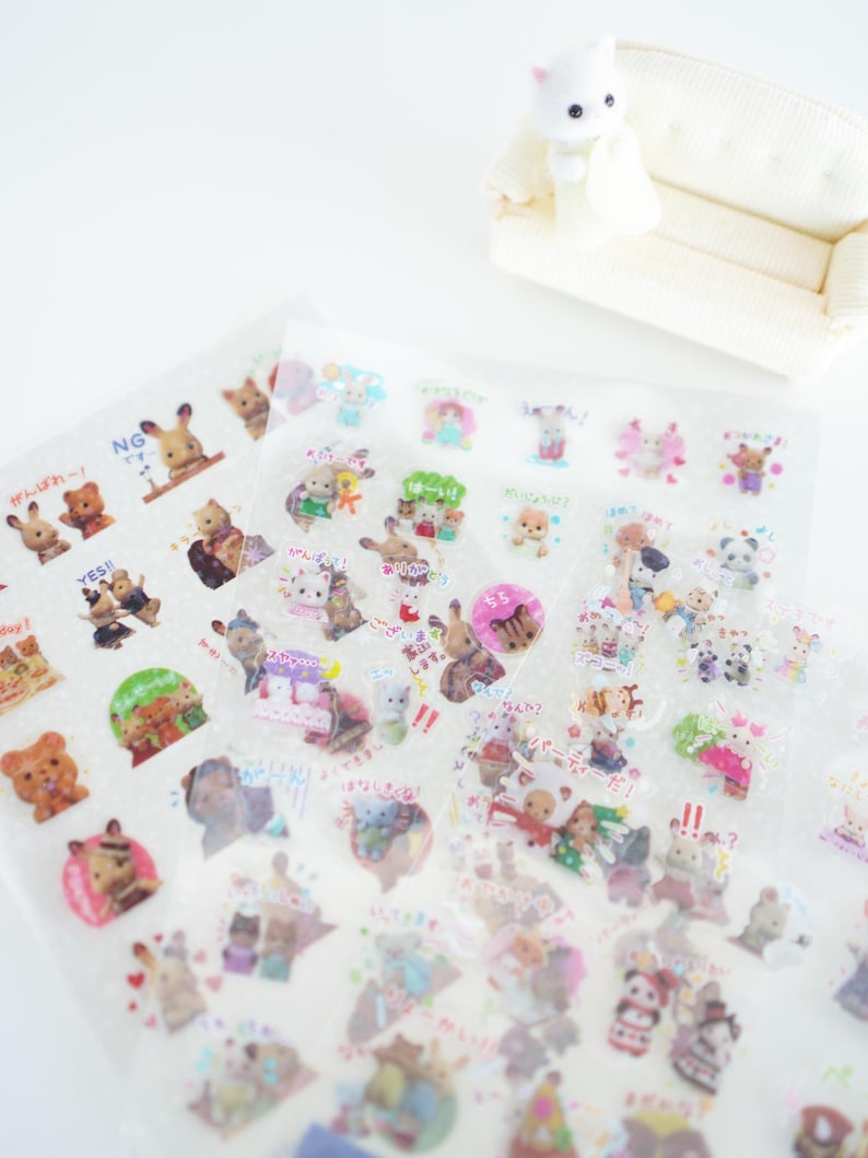 May include: A sheet of clear stickers featuring cartoon animals with Japanese text. The stickers are on a white background and are arranged in rows. The stickers are in a variety of colours and feature different animals, including bears, rabbits, and cats.
