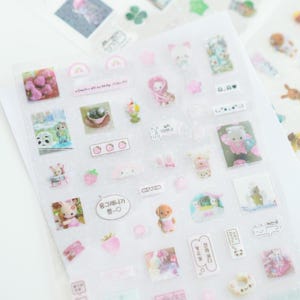 May include: A sheet of clear stickers with a variety of cute illustrations. The stickers feature animals, hearts, strawberries, and other designs. The stickers are perfect for adding a touch of whimsy to your planner, journal, or other projects.
