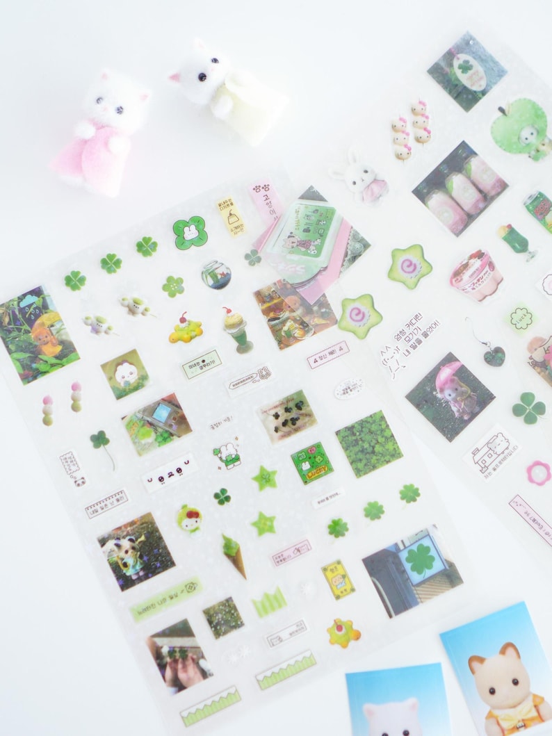 May include: A sheet of clear stickers with various designs, including four-leaf clovers, stars, and small images of animals and plants. The stickers are on a white background.