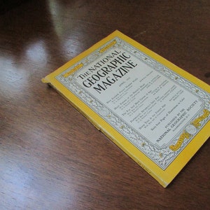 May include: A yellow and white magazine cover for the National Geographic Magazine, April 1951 issue. The cover features text about New Zealand, Hays Kansas, the Fur Seal, Portsmouth, and Sheep Trek in the French Alps. The magazine is published by the National Geographic Society.