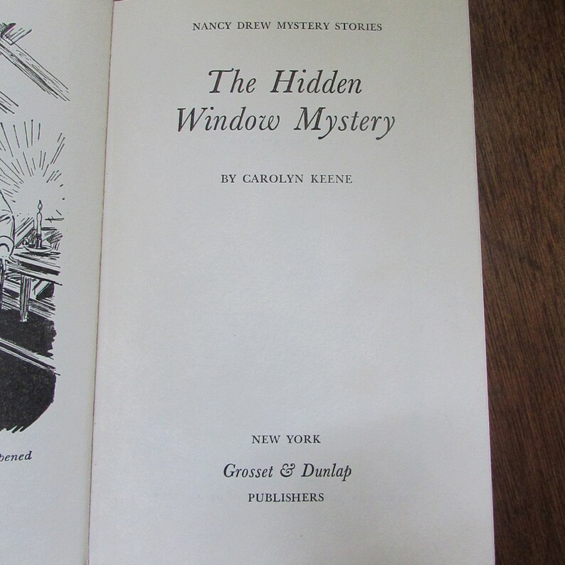 May include: The cover of a Nancy Drew mystery book titled "The Hidden Window Mystery" by Carolyn Keene. The book is published by Grosset & Dunlap in New York.