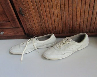 May include: A pair of white leather sneakers with white laces. The shoes have a simple design with a rounded toe and a low top.