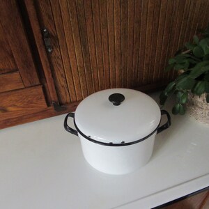 May include: White enamel pot with a black rim and lid. The pot has a black knob on the lid and small black dots around the rim.