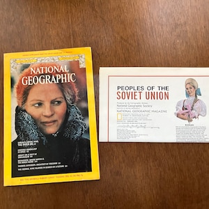 May include: A yellow National Geographic magazine cover featuring a woman in a fur-lined hood. The cover text reads "National Geographic" and "The River Or." The magazine is next to a white pamphlet with the title "Peoples of the Soviet Union" and a photo of a woman in traditional dress.