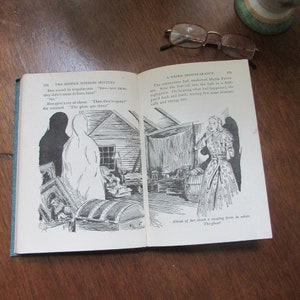 May include: A black and white illustration of a ghost in a book about a ghost story. The text in the book reads "The Hidden Window Mystery" and "A Weird Disappearance".