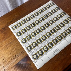 May include: A sheet of Edgar Lee Masters commemorative stamps. Each stamp features a portrait of the poet within a gold-colored frame. The stamps are arranged in a grid pattern on a white sheet, with the text "MAIL EARLY IN THE DAY".