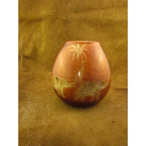 May include: A brown ceramic gourd with a carved design of two elephants and a palm tree. The gourd is a traditional South American vessel used for drinking mate.