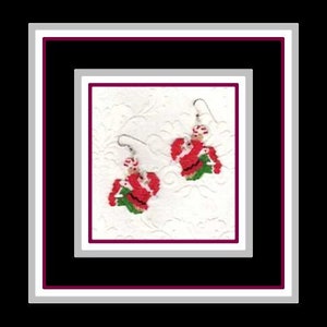 May include: A pair of red and green Christmas-themed earrings with a white bead accent. The earrings are shaped like a Santa Claus figure.