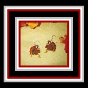 May include: A pair of dangle earrings featuring a beaded turkey design. The turkeys are brown with red accents and white eyes. The earrings are on a white background.