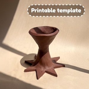 May include: A handmade, brown clay planter with a star-shaped base and a flared top. The planter has a rustic, earthy aesthetic. The text "Printable template" is in a white dotted oval above the planter.