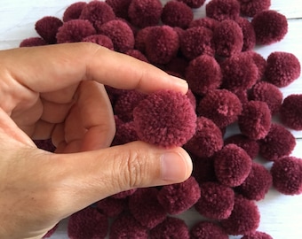 May include: A large pile of burgundy pom-poms. The pom-poms are soft and fluffy, and they are perfect for adding a touch of colour and texture to any craft project.