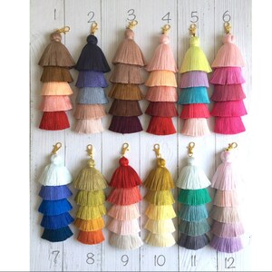 Puede incluir: Doce llaveros de borla multicolores con anillos dorados. Cada llavero tiene tres capas de borlas de diferentes colores. Los llaveros están numerados del 1 al 12.