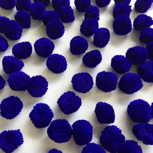 Peut inclure: Plusieurs pompons bleu foncé, de forme sphérique, dispersés sur une surface blanche. Ces décorations duveteuses sont fabriquées à partir d'un matériau doux, parfaites pour les projets de bricolage ou pour ajouter une touche de couleur. Les pompons varient en taille et en texture.