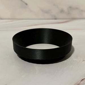May include: A black plastic ring, possibly a coffee filter holder.